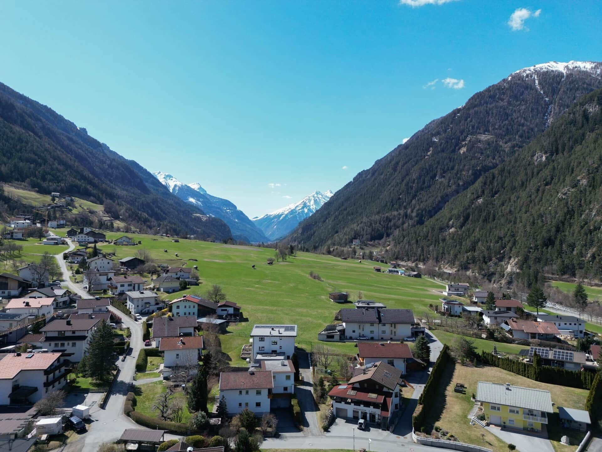 Ein Dorf in den Bergen mit Häusern, einer Straße und einem Tal.