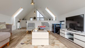 Un appartement-loft spacieux avec de hauts plafonds, un grand téléviseur et un coin salon confortable.