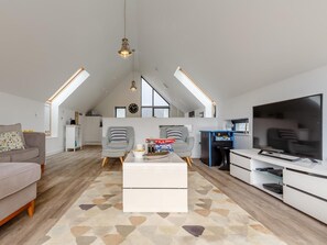 Ein großzügiges Loft-Apartment mit hohen Decken, einem großen Fernseher und einer gemütlichen Sitzecke.