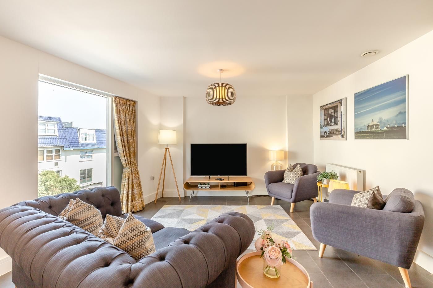 A modern living room with a large flat-screen TV, two sofas, a coffee table, and a floor lamp.