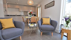 Ein modernes Wohnzimmer mit zwei grauen Sesseln, einem kleinen Couchtisch und einem gelben Teppich.