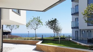 Ein moderner Wohnkomplex mit Meerblick, Sitzgelegenheiten im Freien und einem gepflegten Garten.