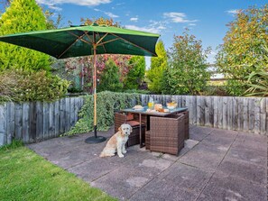 Un patio con una mesa, sillas y un perro.