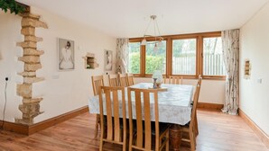 Un espace repas comprenant une table, des chaises, un élément décoratif en pierre et des fenêtres.
