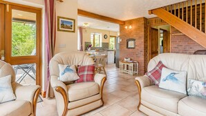 Een gezellige woonkamer met een open haard, een eethoek en een keuken op de achtergrond.