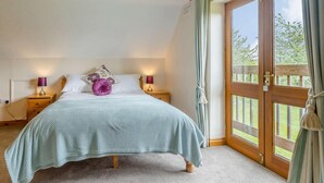 Een slaapkamer met een bed, nachtlampjes, een raam en een deur.