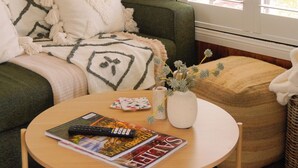 A cozy living room with a green sofa, a round wooden coffee table, and a painting on the wall.