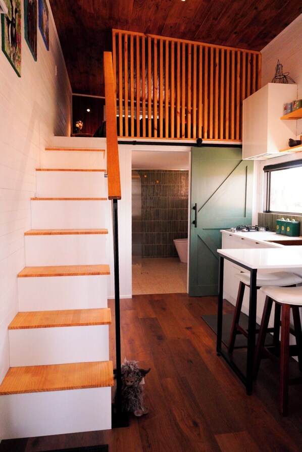 A staircase leading to a loft area with a kitchen and a bathroom visible in the background.