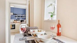 Ruokapöytä on katettu valkoisella kulholla, viinilasilla ja pullolla roséviiniä.