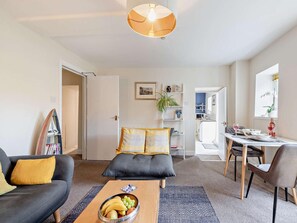 A modern living room with a sofa, coffee table, and dining area. - 1 Bed in Aberaeron (oc-49261) (Aberaeron)