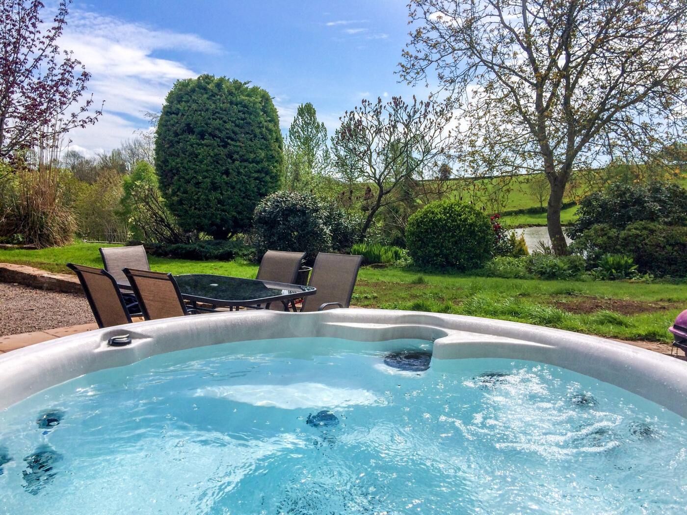 Ein Whirlpool in einem Garten mit Stühlen und einem Tisch.