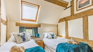 Een slaapkamer met twee bedden, dakraam, houten balken en een ingelijst schilderij aan de muur.
