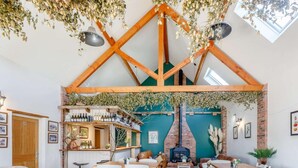 Een rustiek interieur met zichtbare houten balken, een metselstenen openhaard en een bar met flessen.