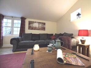 Ein gemütliches Wohnzimmer mit einer Couch, einem Couchtisch und einem Bild an der Wand.
