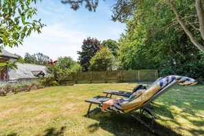 Ein Garten mit umzäunter Fläche, Rasen und Baum.
