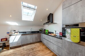 Eine moderne Küche mit Oberlichter, Einbauofen und Holzboden.