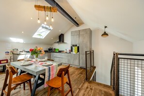 Eine moderne Küche mit Essbereich, ausgestattet mit einem Holztisch, Stühlen und einer Pendelleuchte.