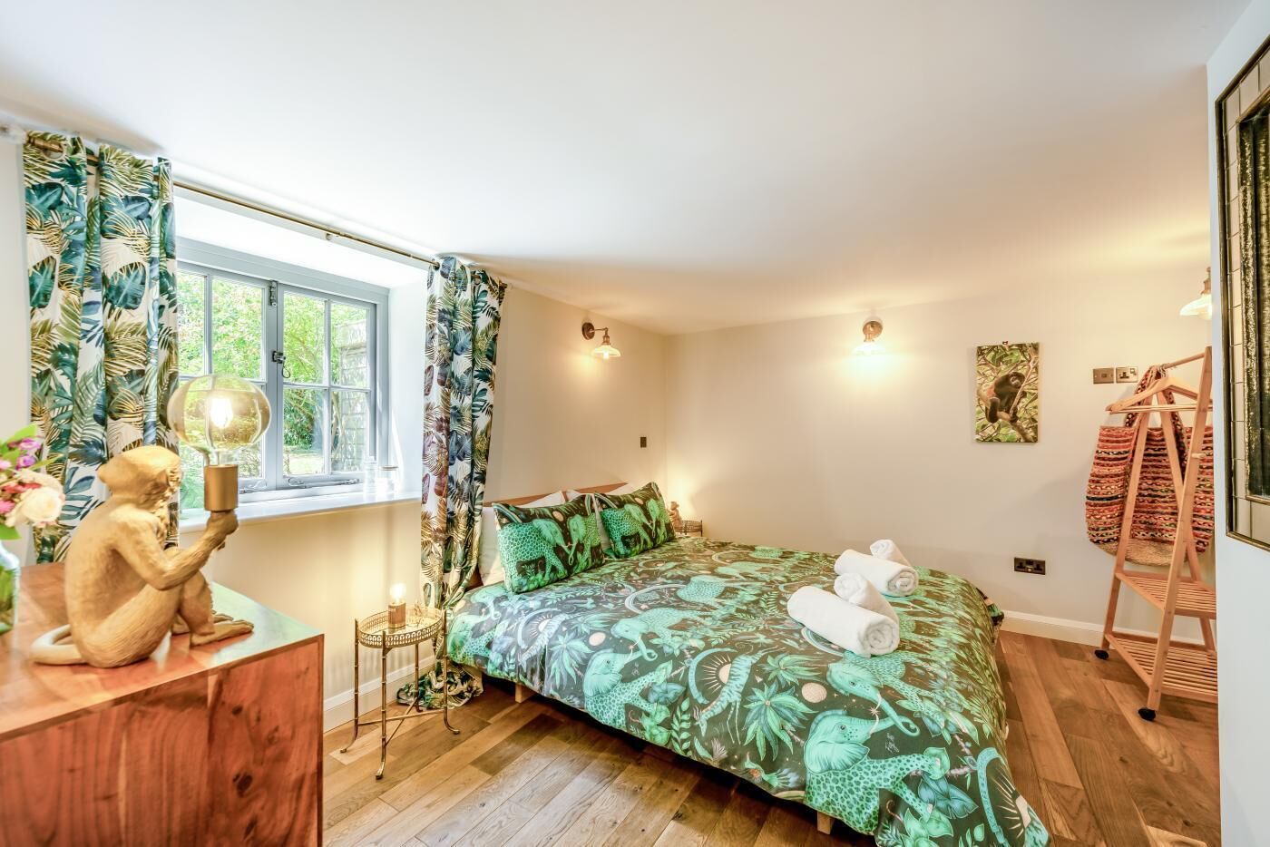 A bedroom with a bed, a dresser, a window, and a wall-mounted lamp.