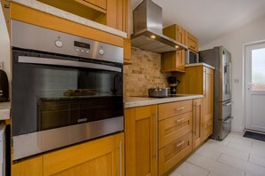 A modern kitchen with a built-in oven, a microwave, and a refrigerator. - 3 Bed in Dorchester (oc-49005) (Owermoigne)