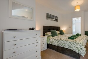 A bedroom with a bed, a dresser, a mirror, a painting, and a door. - 3 Bed in Dorchester (oc-49005) (Owermoigne)