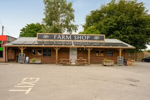 A farm shop with a rustic wooden facade, a signboard, and a bench outside. - 3 Bed in Dorchester (oc-49005) (Owermoigne)