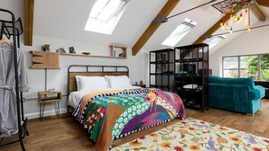 A bedroom with a bed, a colorful rug, a teal sofa, a wooden cabinet, and a skylight. - 1 Bed in Umberleigh (oc-49554) (High Bickington)