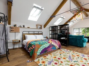 A bedroom with a bed, a colorful rug, a teal sofa, a wooden cabinet, and a skylight. - 1 Bed in Umberleigh (oc-49554) (High Bickington)