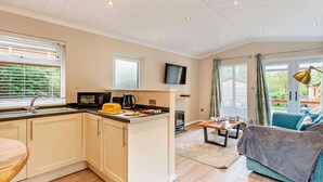 Een moderne keuken met een centraal eiland, een eetgedeelte met een tafel en stoelen, en een gezellige woonkamer met een bank en een televisie.