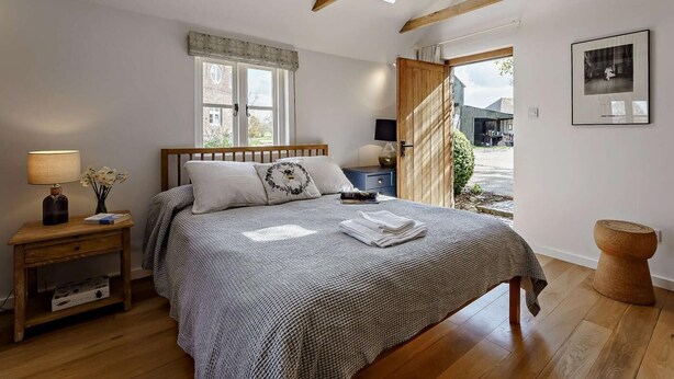 Ein Schlafzimmer mit Bett, Nachttischen, einem Fenster und Blick ins Freie.
