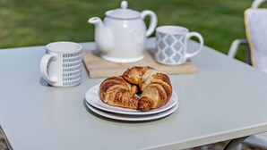 Ein Tisch mit einem Teller Croissants, einem Teekessel und zwei Tassen.