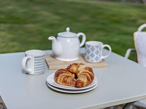 Ein Tisch mit einem Teller Croissants, einem Teekessel und zwei Tassen.