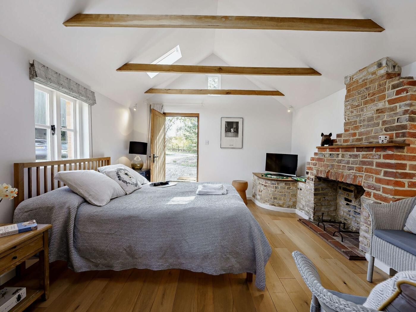 Ein Schlafzimmer mit Bett, Fernseher, Kamin und Blick ins Freie.
