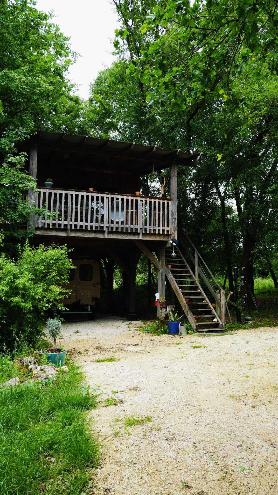 A wooden cabin with a balcony and a staircase leading to a deck.