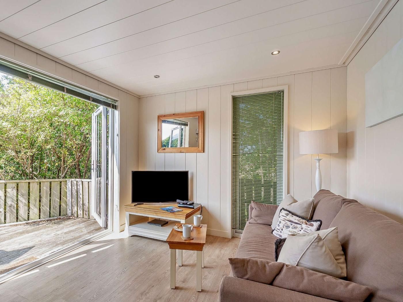 A modern living room with a flat-screen TV, a wooden coffee table, and a beige sofa.