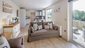 A spacious living area with a sofa, a dining table, and a kitchen in the background. - 2 Bed in Conwy (oc-50284) (Ty'n-y-groes)