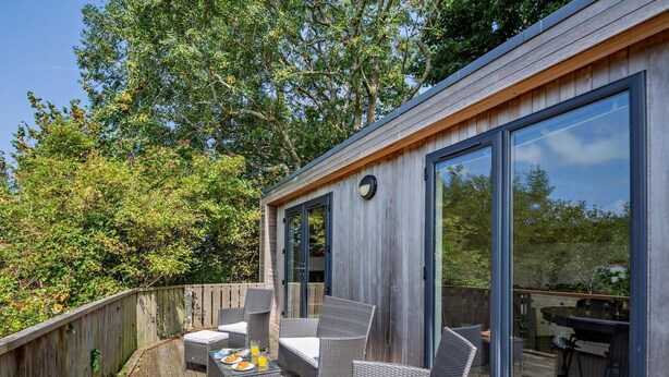 A deck with wicker furniture and a table set for breakfast. - 2 Bed in Conwy (oc-50284) (Ty'n-y-groes)