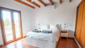 Une chambre à coucher comprenant un lit, des tables de chevet, une commode, une fenêtre et un appareil de climatisation.