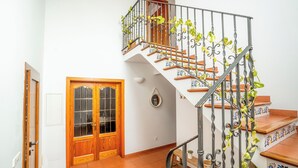 Un escalier en colimaçon orné de rampes en métal ouvragé et une porte en bois dotée de panneaux de verre.