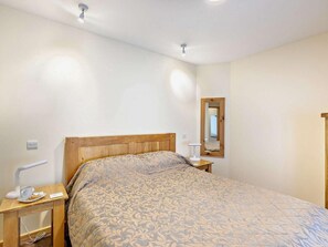 A single bed with a patterned bedspread, a bedside table with a lamp, and a mirror on the wall. - 1 Bed in Ross -on- Wye (oc-49910) (Walford)