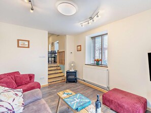 A living room with a sofa, a coffee table with a board game, a radiator, and a window with blinds. - 1 Bed in Ross -on- Wye (oc-49910) (Walford)