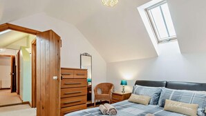 Un dormitorio con cama, cómoda, silla, mesita de noche y ventana.