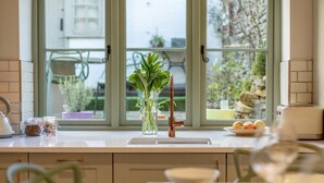 Eine Küche mit Fenster, einer Pflanzvase, einem Wasserkocher, Vorratsgläsern und einem Toaster.