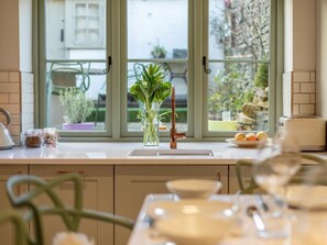 A kitchen with a window, a vase with plants, a kettle, jars, and a toaster. - 3 Bed in Cheltenham (oc-49965) (Lower Swell)