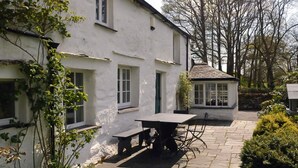 A white building with a stone patio, a table, and chairs. - 4 Bed in Hawkshead (oc-llh02) (Near Sawrey)