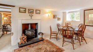 A cozy room with a fireplace, a dining table with chairs, and a rug. - 4 Bed in Hawkshead (oc-llh02) (Near Sawrey)