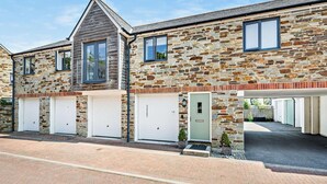 A two-story house with stone walls, a sloped roof, and three garage doors. - 2 Bed in St. Austell (oc-50111) (Charlestown)