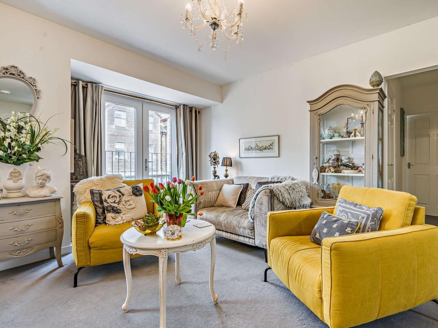 A living room with a sofa, armchair, and a table with flowers.