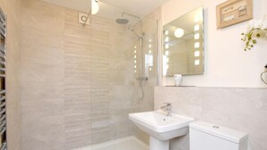 Ein modernes Badezimmer mit einer Glaskabine zur Dusche, einem Standwaschbecken und einer Toilette.