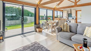 Ein modernes Wohnzimmer mit einem grauen Sofa, einem Couchtisch und einem Essbereich mit Stühlen.