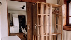 Ein Zimmer mit einem Holfischschrank, einem weißen Schreibtisch und einem Bett mit grüner Decke.